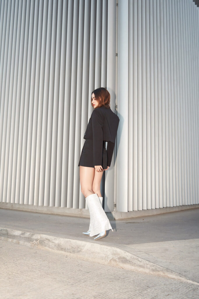 Ana Karina is seen in a dynamic pose wearing sparkling silver boots by Avice